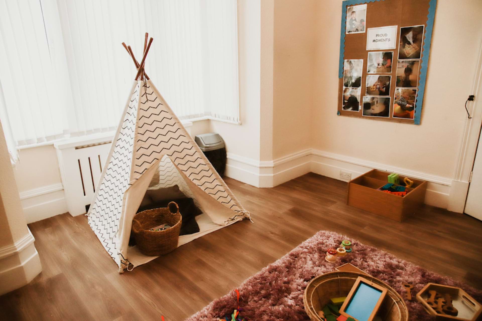 Cozy play corner at Kindred Bromley North Nursery and Pre-school A cozy play corner at the nursery with a teepee tent, a furry rug, and a basket of toys.