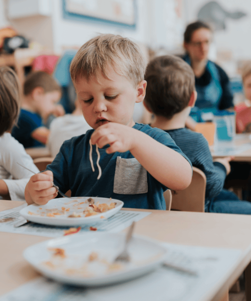 A boy eats a plate of spaghetti