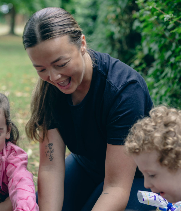 An adult and children are gathered around laughing and playing