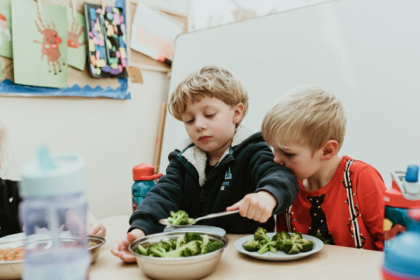 two children are serving themselves some broccoli